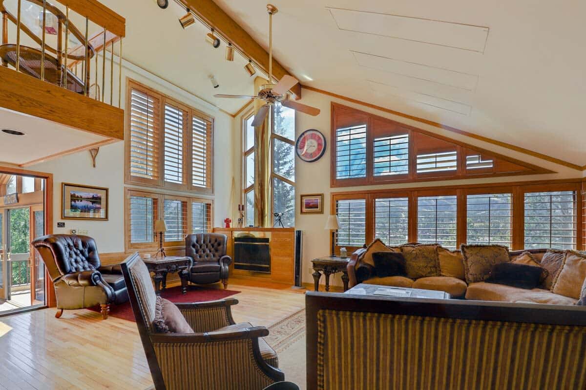 Third floor living room with sectional sofa, large flat screen TV, and wood burning fireplace