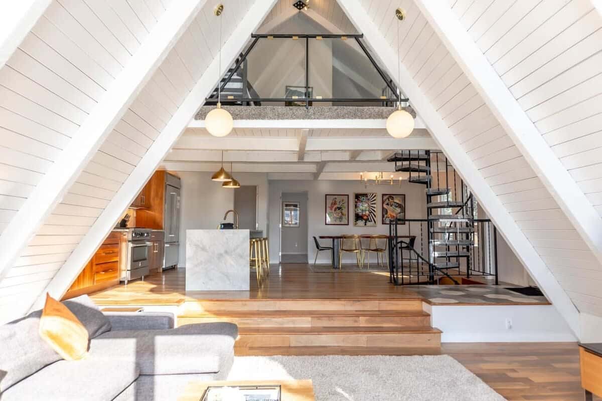 The main floor of this modern, newly-renovated A-Frame features an open living/kitchen/dining area complete with stunning art and furnishings, a spacious large deck, and an unbeatable view, perfect for your group to relax in style.