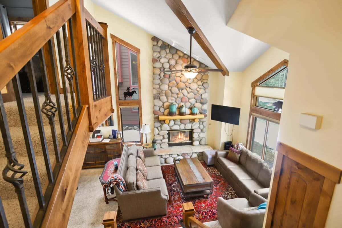 The living room boasts a striking stone fireplace, vaulted ceilings, large windows, two plush couches, including one with a queen-size pullout bed, an armchair, a roomy coffee table and a 42-inch flat-screen TV.