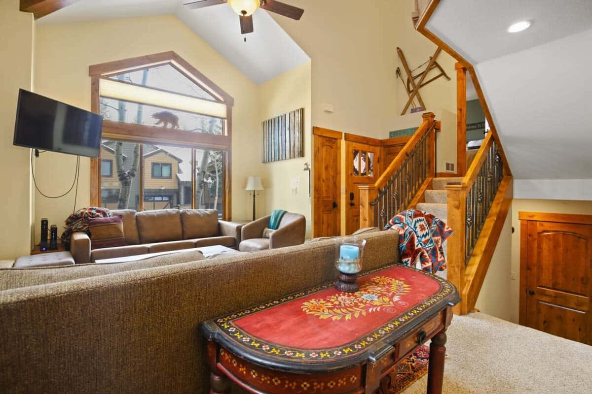 The living room boasts a striking stone fireplace, vaulted ceilings, large windows, two plush couches, including one with a queen-size pullout bed, an armchair, a roomy coffee table and a 42-inch flat-screen TV.