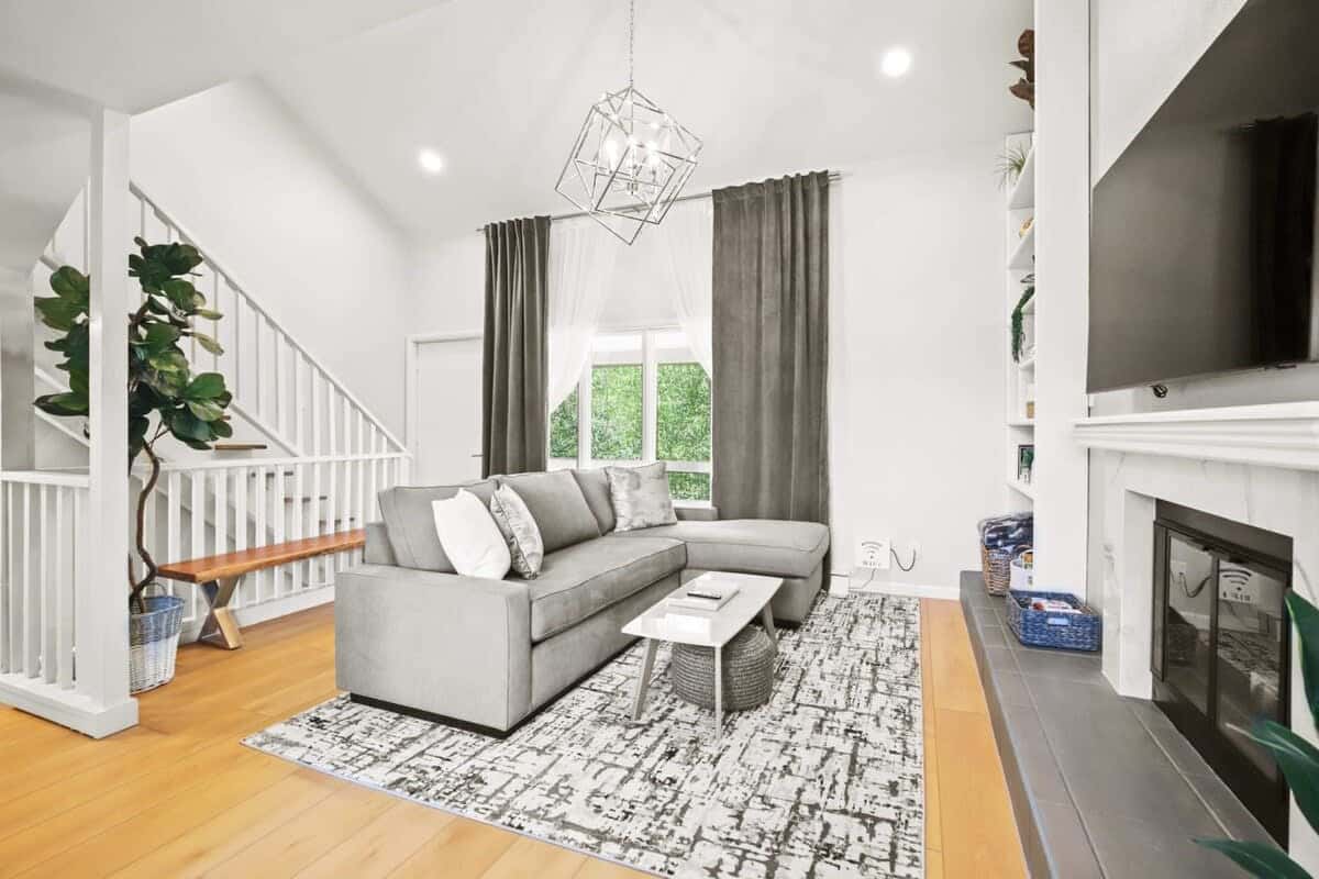 The gorgeous, light-filled living room features high ceilings, built-in bookshelves, flat-screen TV, coffee table and a roomy sectional that doubles as a queen-size, pull out bed.