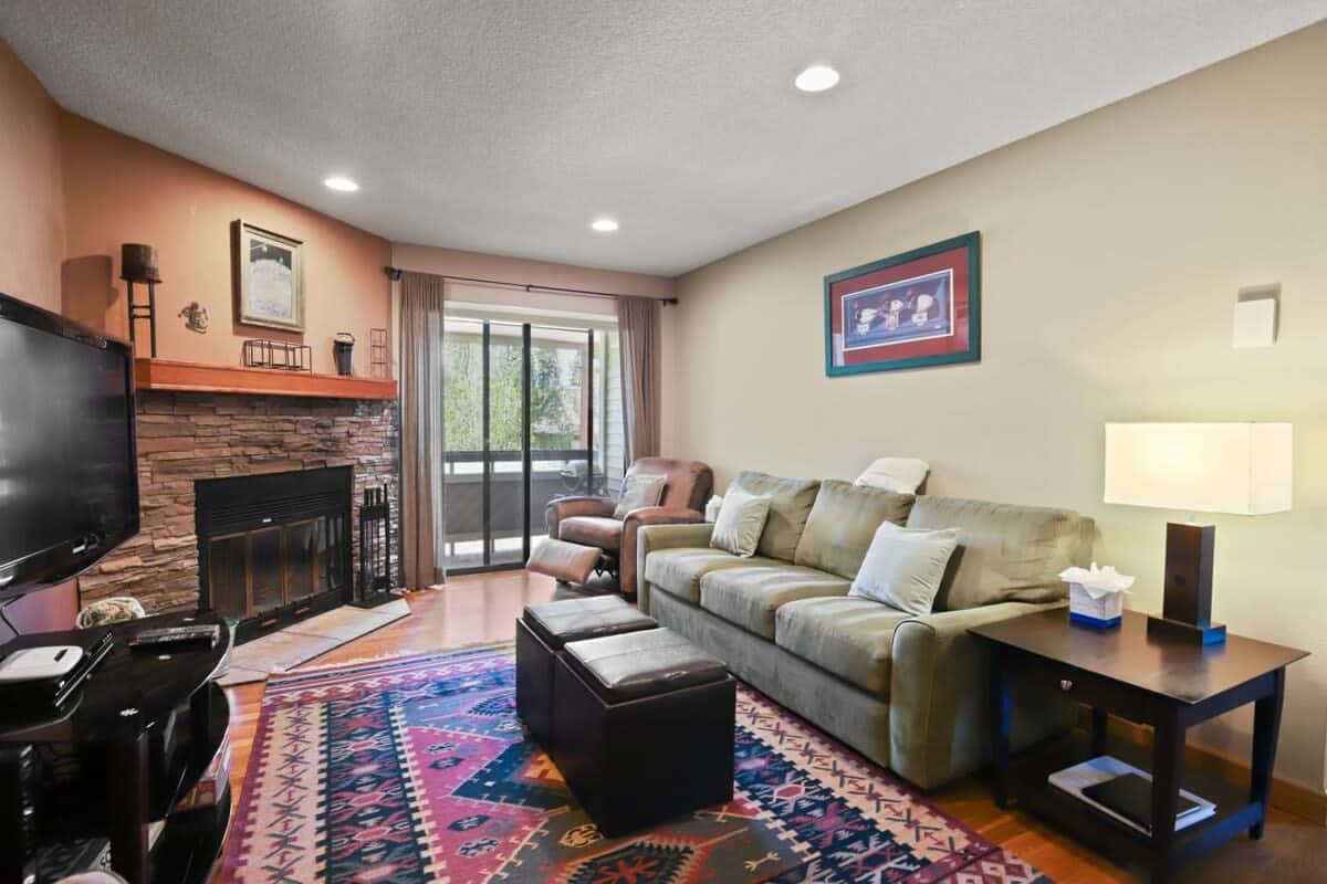 The inviting living room features a plush couch that doubles as a queen-size, pull out bed, cozy recliner, reading chair and two ottomans. A beautiful stone fireplace, media console & flat-screen TV round out the space.