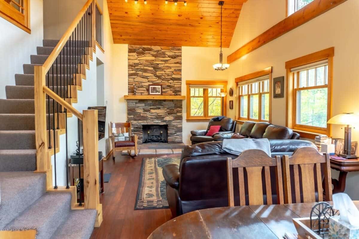 View of the living area, fireplace and a set of stairs going up to the second level of the home.