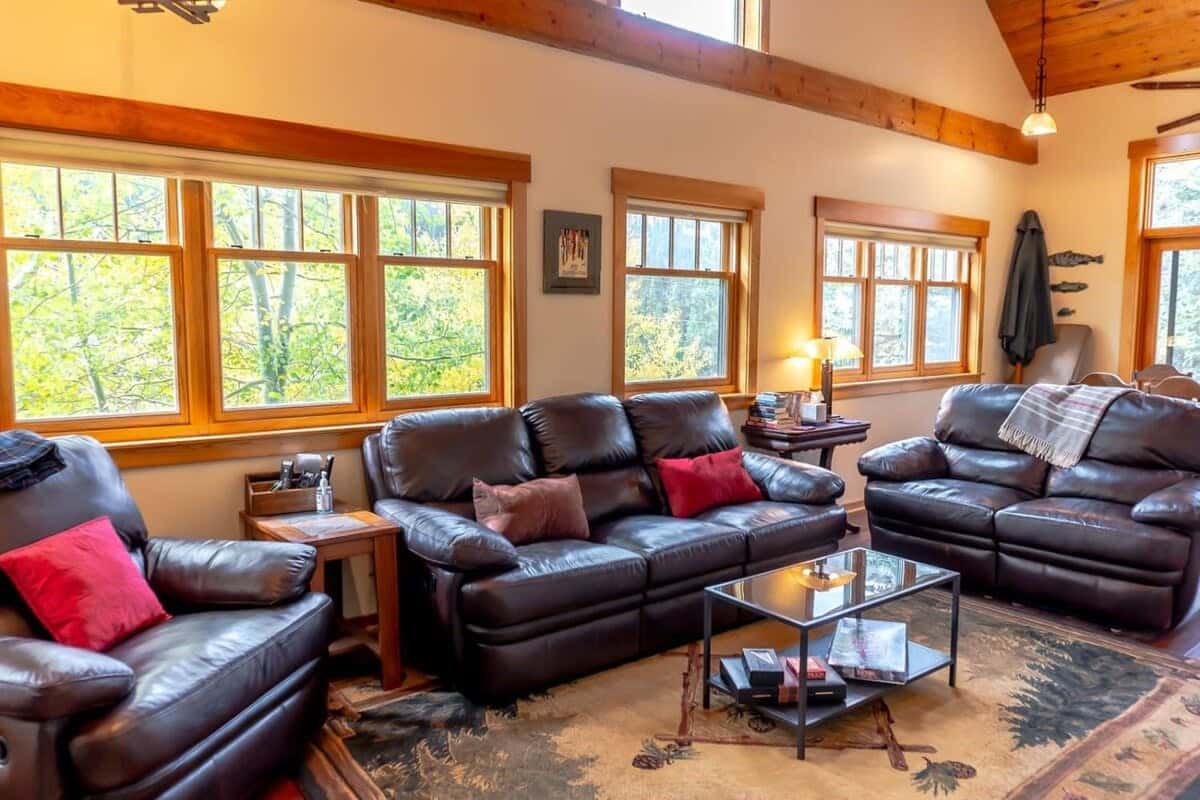 Our open-concept living area with sets of sofas; a warm fireplace; a 42-inch flat-screen TV, and abundant natural light with nature views!