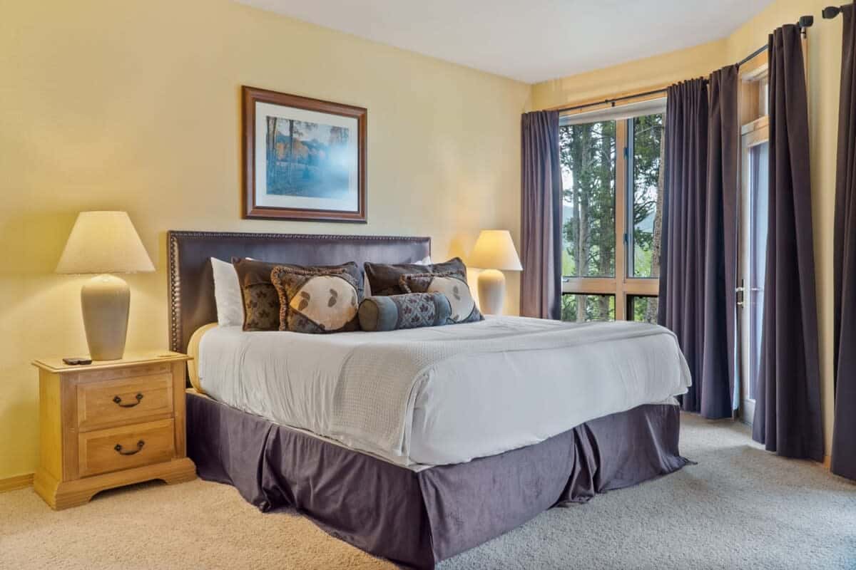 The master suite boasts impressive views out of the soaring windows, a king-size bed, a mounted TV and an attached full bathroom.