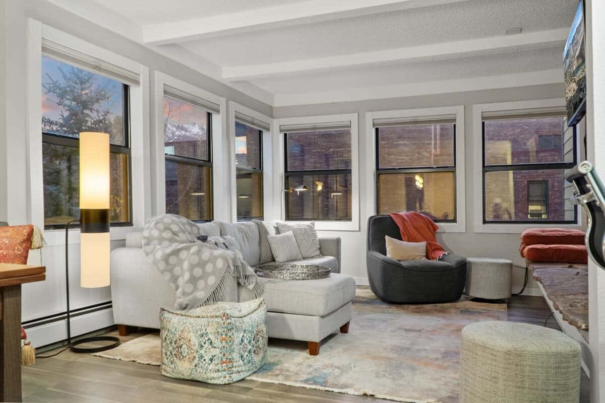 The inviting living room is filled with natural light and charm boasting mountain views, a cozy fireplace, and plush furnishings.