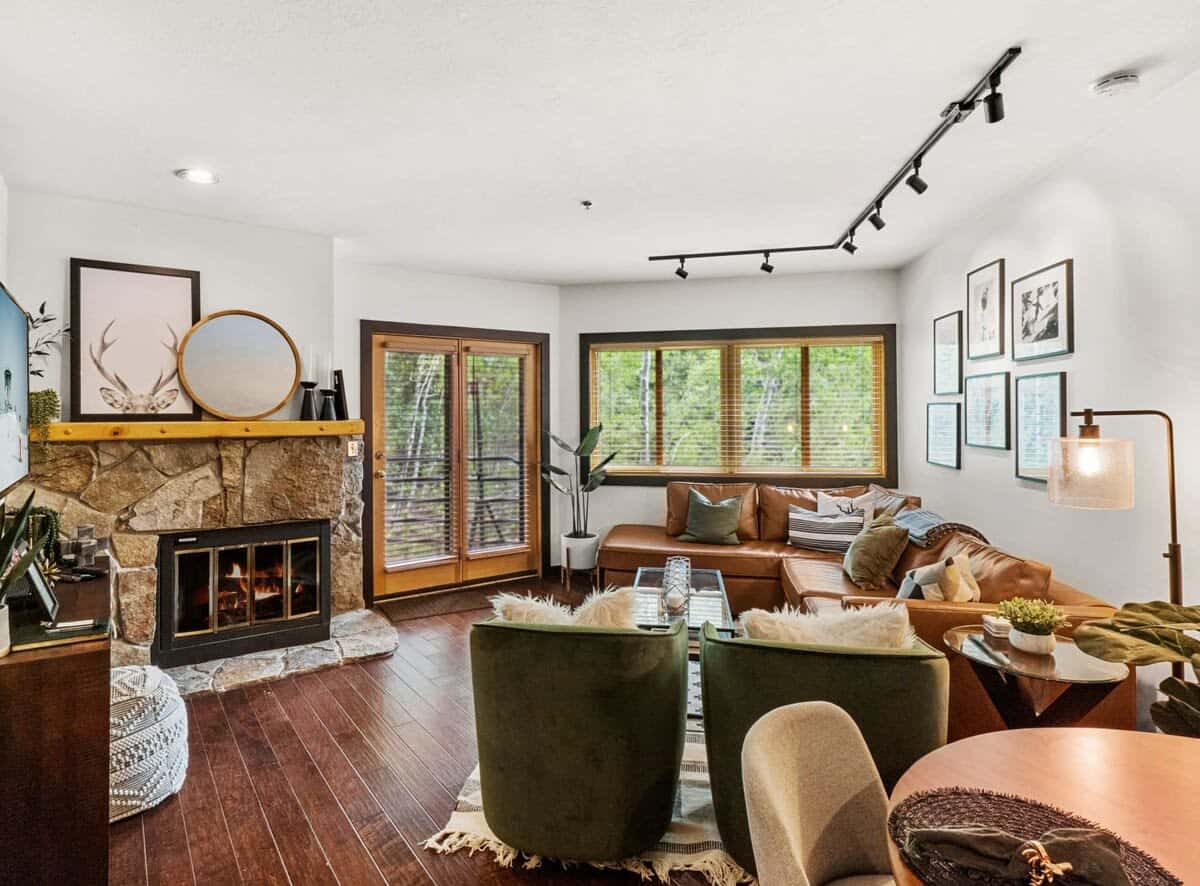 The gorgeous living room boasts a spacious leather sectional with a queen-size, pullout bed, two plush armchairs, a coffee table, end table, floor lamp, flat-screen TV, console table and a striking stone fireplace.