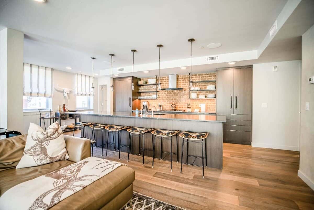 Additional seating for six more is nearby at the large kitchen island, which doubles as a convenient serving area to the living and dining rooms. The kitchen is a modern space with an exposed brick wall and high-end finishes.