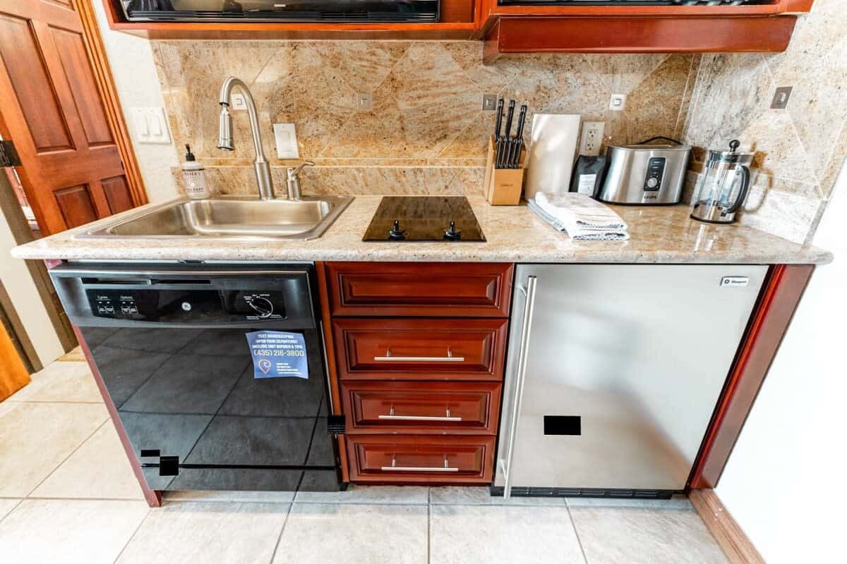 The kitchenette includes a stainless steel mini-fridge, microwave, dishwasher, and an electric double-stove top providing all the necessities to enjoy a meal at home.