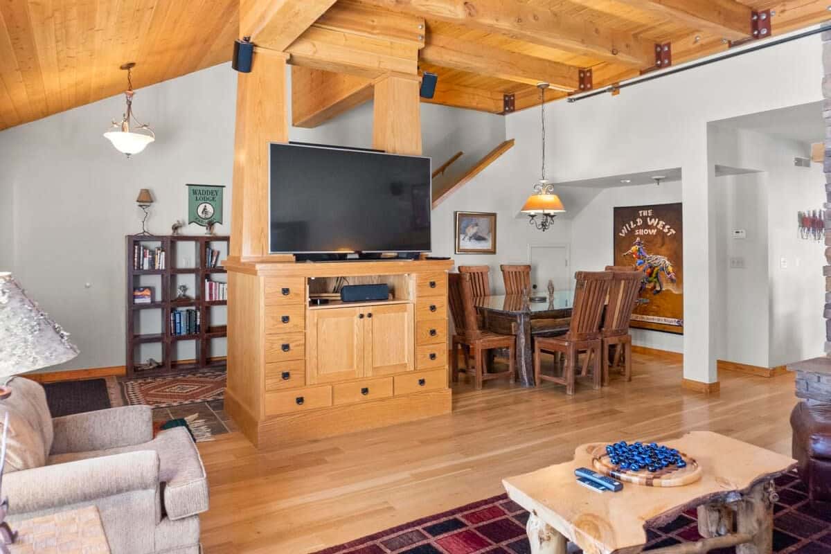 The second living room features a 60” smart TV over a cabinet storage unit with a dining room table with seating for six tucked into the corner.