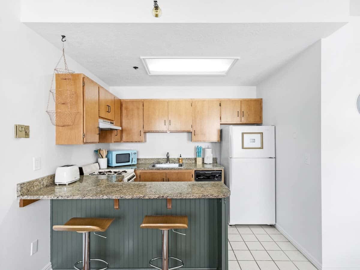 The view into the kitchen where you will find a kitchen bar with seating for two and all the basic appliances and cookware to prepare simple meals at home.