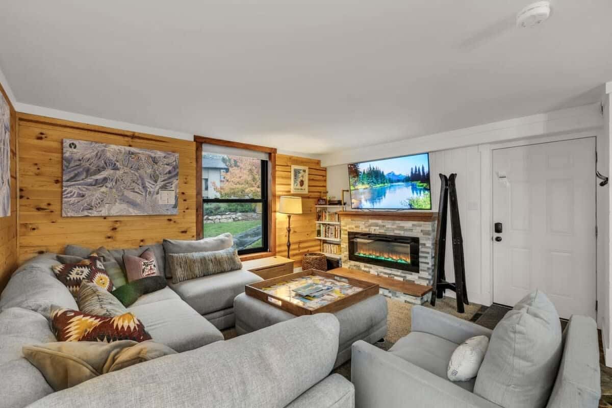 The stylish living room is the perfect spot to unwind after a busy day of adventures with a plush sectional sofa, an electric fireplace, and a mounted 55” TV.