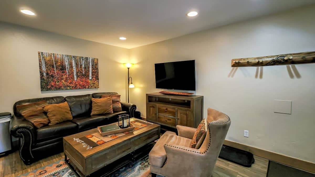 The cozy living area boasts a leather sofa, coffee table, armchair, a media console and a flat-screen TV. The sofa can convert into a bed, if needed.