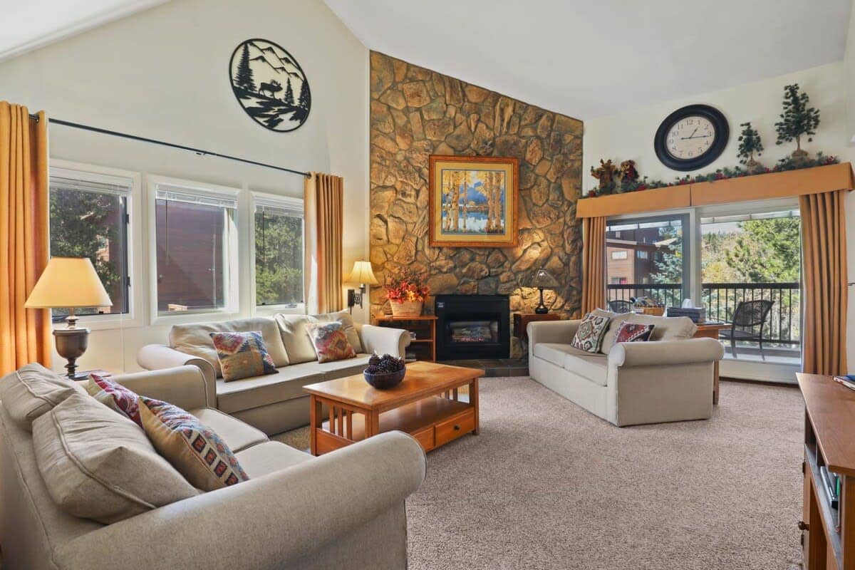 Enjoy the open-space living area as you relax in one of the three cozy sofas while taking in the high ceilings, impressive stone-finished fireplace, and views out the large windows.