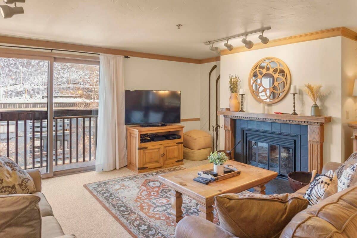 The living room is a cozy and inviting space perfect for relaxing as you warm up by the wood-burning fireplace or watch a show on the 55-inch flat-screen TV.
