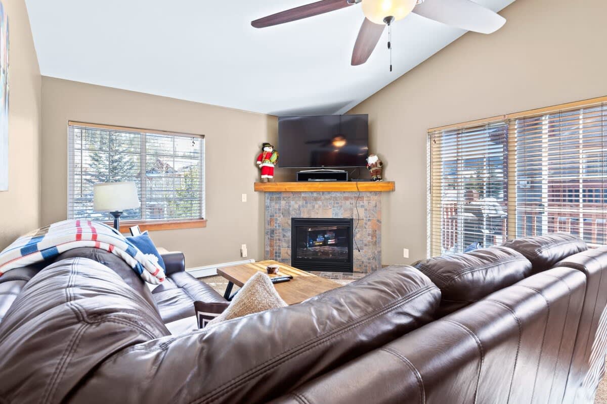Relax in the family room with a large sectional sofa, a flat-screen TV, a warm indoor fireplace, and access to the outdoor balcony