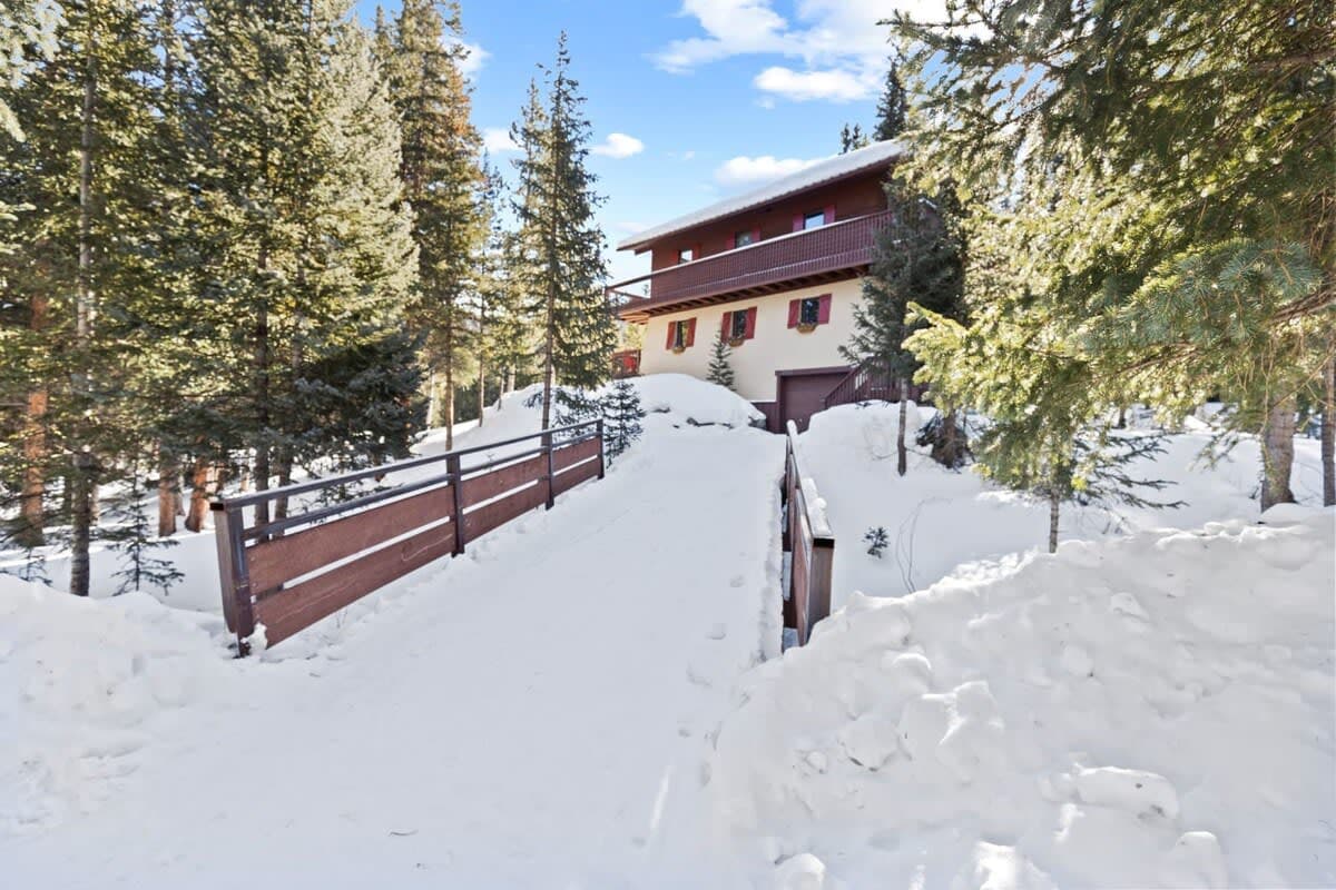 Across the charming bridge, awaits a light-filled mountain home with a wrap-around deck that offers breathtaking views in every direction.