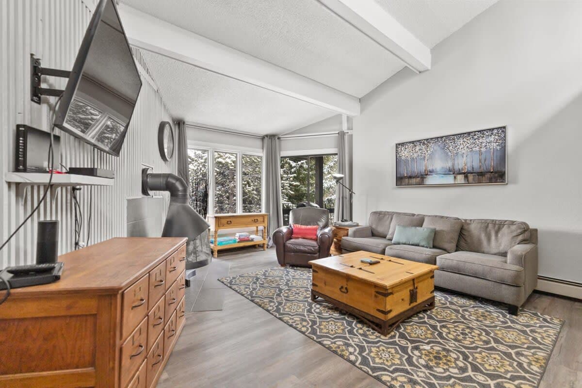 The stunning living area is bathed in light and features beamed ceilings, a unique gas fireplace, a large dresser, 50-inch, flat-screen TV, leather armchair, coffee table and cozy couch that doubles as a queen-size pullout.