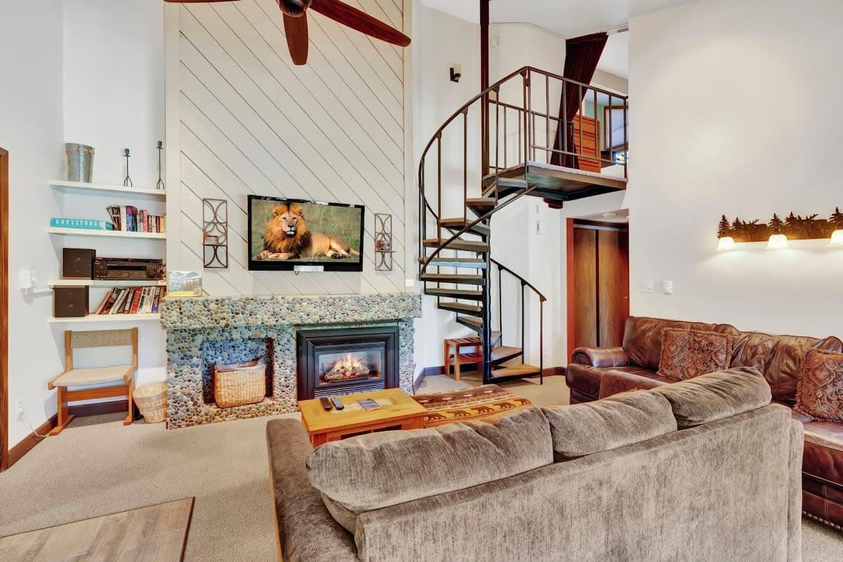 The striking living room features a gas fireplace with river rock accents, a flat-screen TV, leather couch, loveseat, coffee table, ottoman and access to the outdoor balcony. This inviting space is also open to the kitchen/dining area.