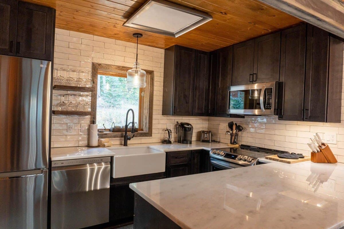 The newly-remodeled kitchen features sleek modern touches, like open shelving, tile backsplash, and stainless steel appliances. It also boasts a coffee maker, toaster, and blender.