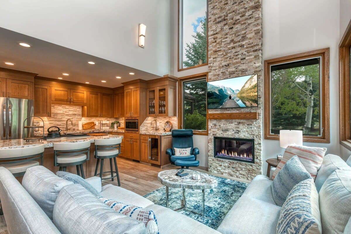 The show stopping living room boasts vaulted ceilings, striking stone fireplace, large flat-screen TV, stylish leather chair and ottoman, roomy sectional, coffee table, lots of natural light and close proximity to the stunning kitchen.