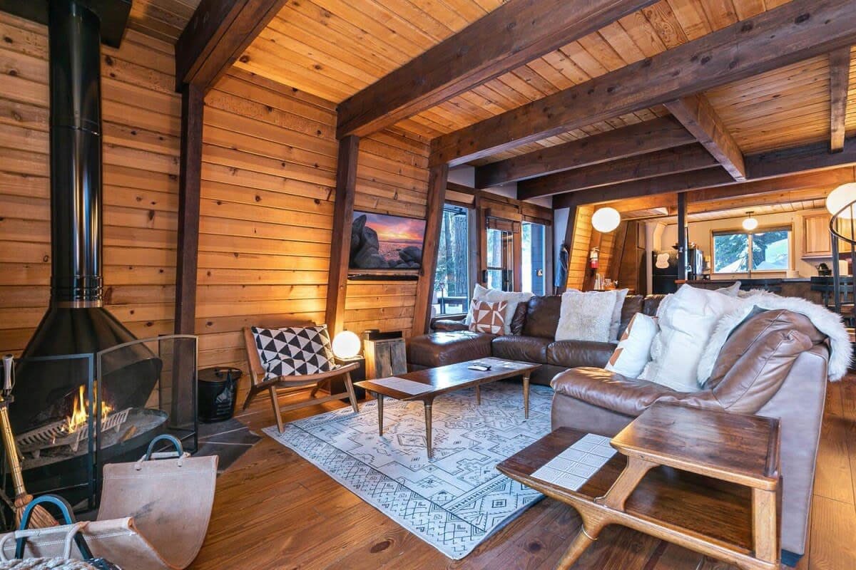 This 4-bedroom cabin is full of rustic mountain charm with beautiful exposed ceiling beams and soaring windows in a tranquil forested setting.