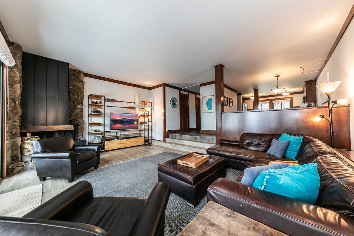 The large living room offers tons of amenities, like a sectional leather sofa, a pair of leather chairs, a Samsung Smart TV, and even a PS5.